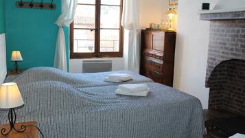 Un dormitorio con dos camas, un aparador de madera, una chimenea y una ventana con cortinas.