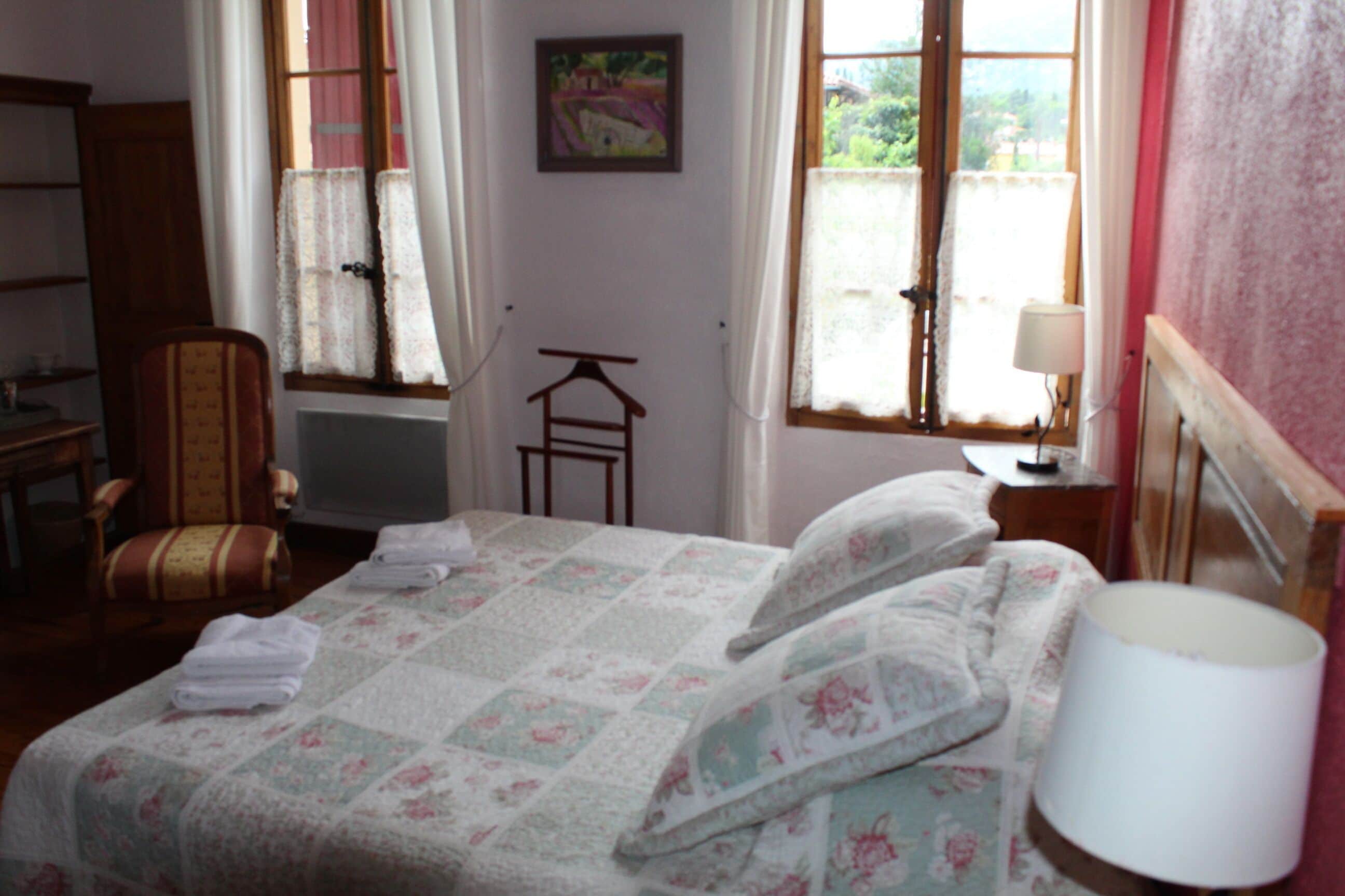 A bedroom with a bed, a chair, a table, and a lamp.