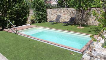 Een seizoensgebonden buitenzwembad en ligstoelen