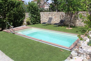 Una piscina al aire libre de temporada, tumbonas