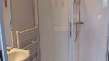 A modern bathroom with a glass-enclosed shower, a white sink, and a towel rack.