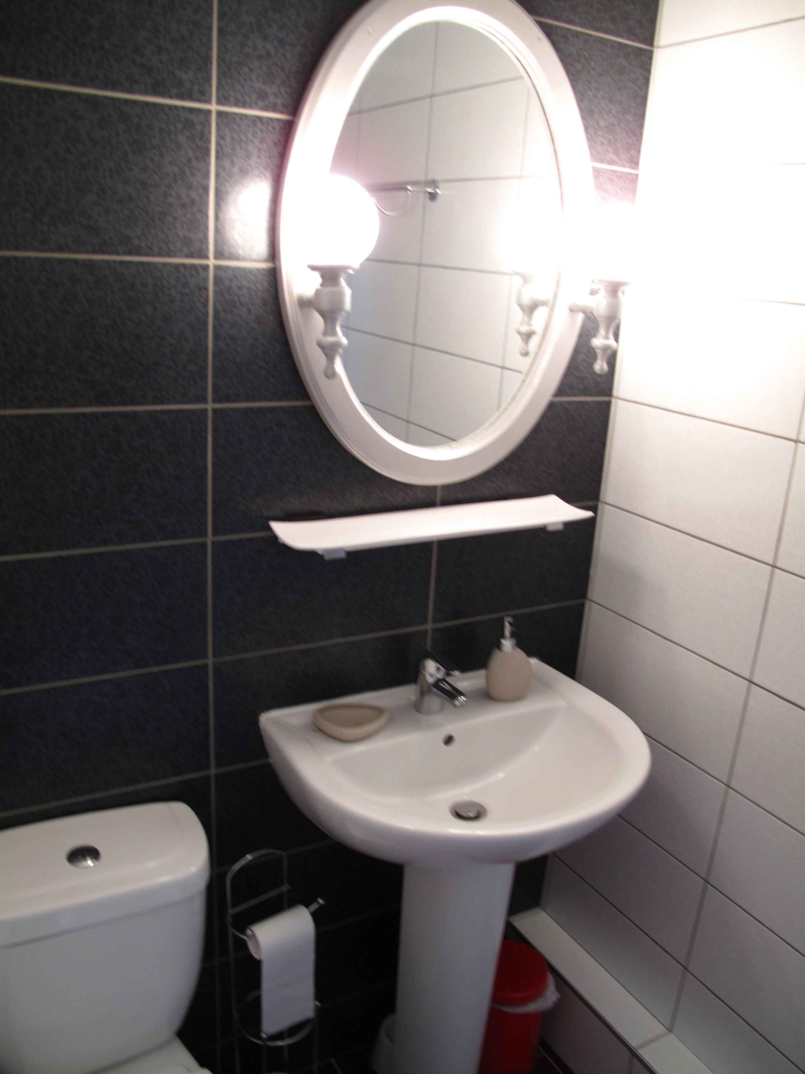 Un baño con un lavamanos blanco, un espejo y un inodoro.