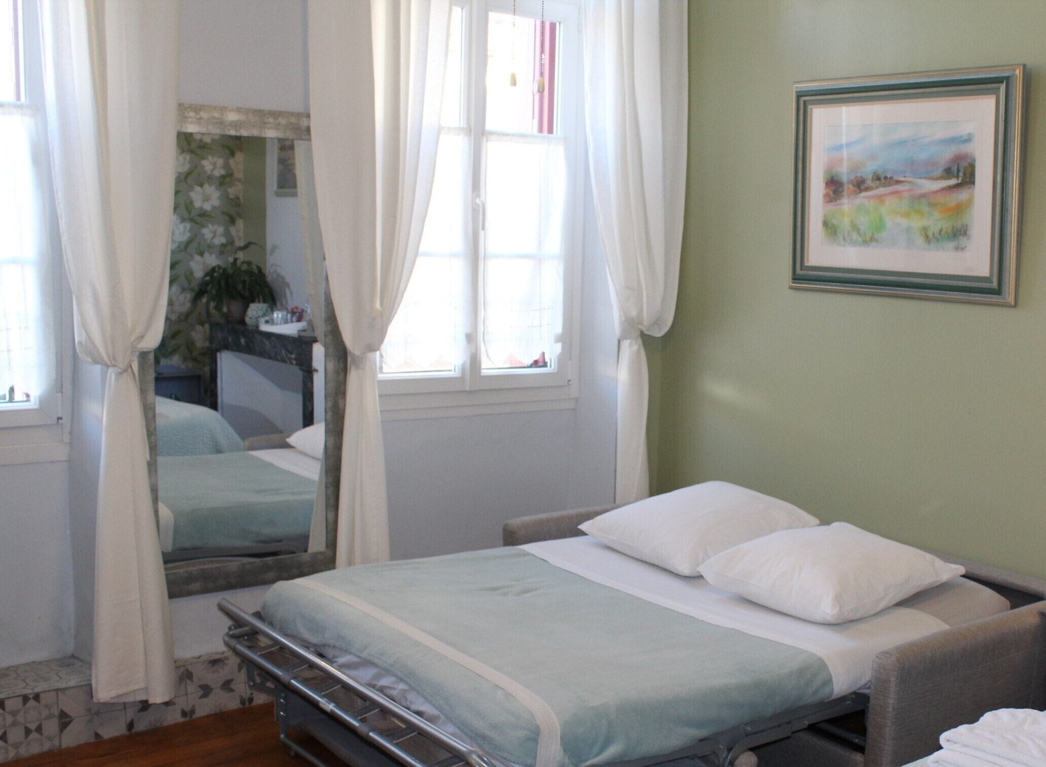 A single bed with a metal frame, white bedding, and a window with curtains.