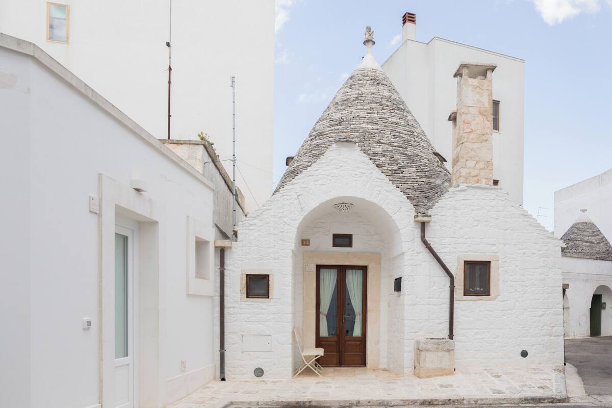 Un bâtiment blanc avec un toit en pierre et un petit porche.
