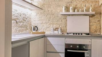 A kitchen with a stone wall, a wooden countertop, and a built-in oven.