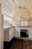 Una cucina con parete in pietra, piano di lavoro in legno e forno a incasso.