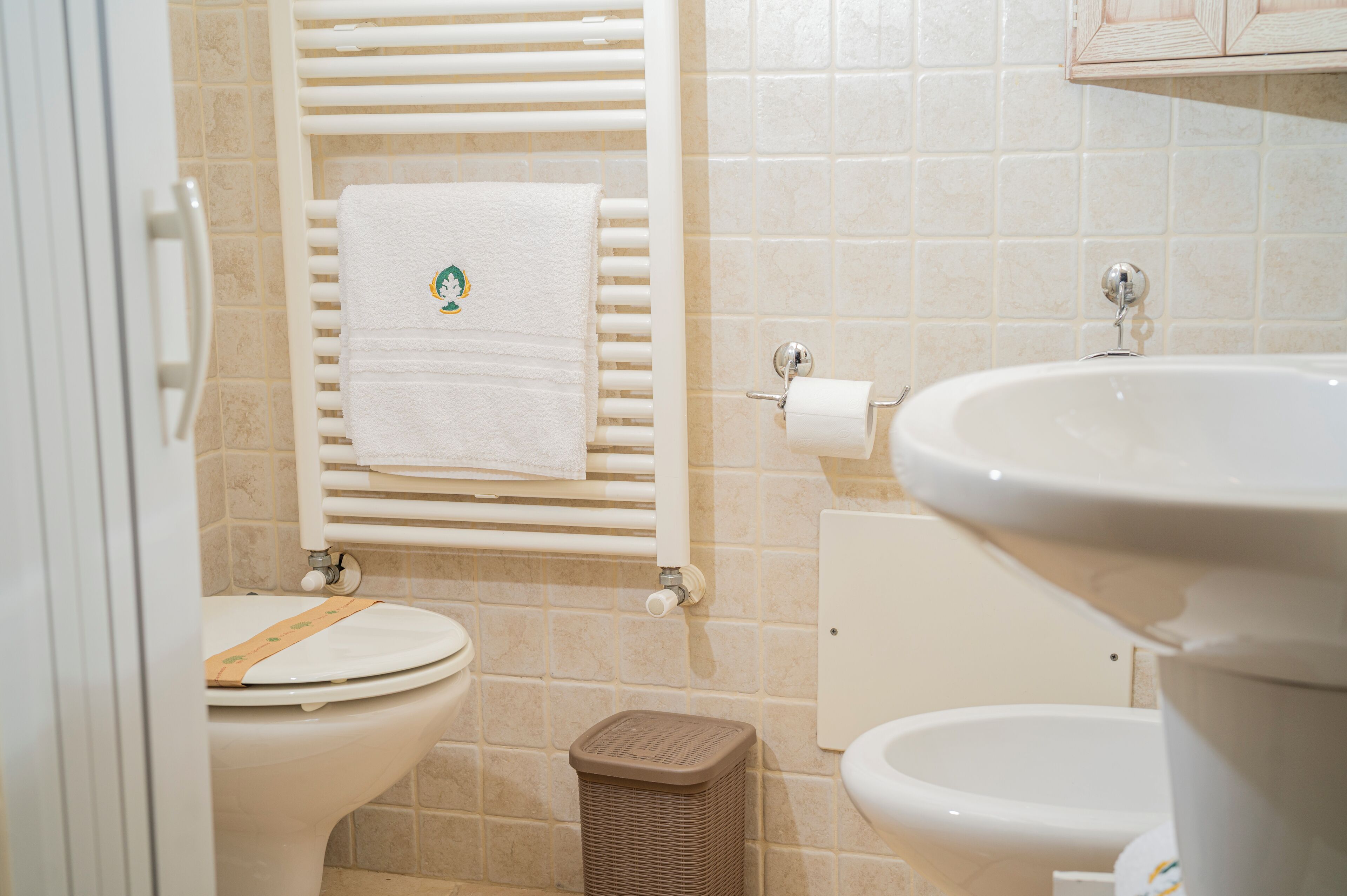 Un bagno con il water, un lavandino e un portasciugamani.