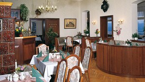 A formal dining room with ornate wood paneling, a chandelier, and a view of the outdoors. - Panoramahotel Wolfsberg (Reinhardtsdorf-Schoena)
