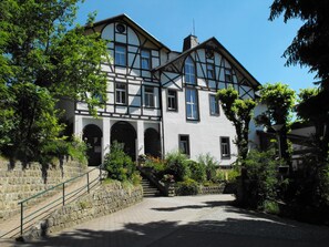 Un edificio tradicional de entramado de madera con amplias ventanas y una escalera de piedra que conduce a la entrada.