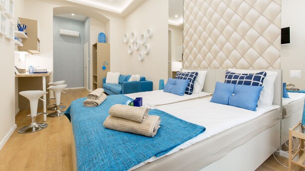 A modern hotel room with a large bed, two bedside tables, a desk, and a seating area with chairs. - Budapest Holiday Colours (Budapest)
