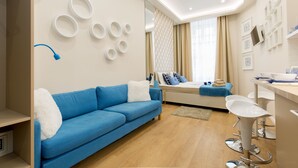 A modern living room with a blue sofa, a white coffee table, and a bar area with white stools. - Budapest Holiday Colours (Budapest)