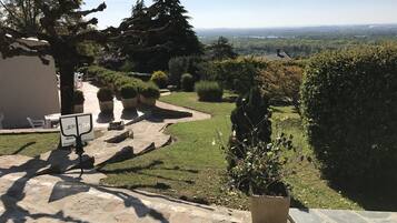 Un sendero de piedra que conduce a un área de estar al aire libre, rodeado de plantas en macetas y una vista de un paisaje lejano.