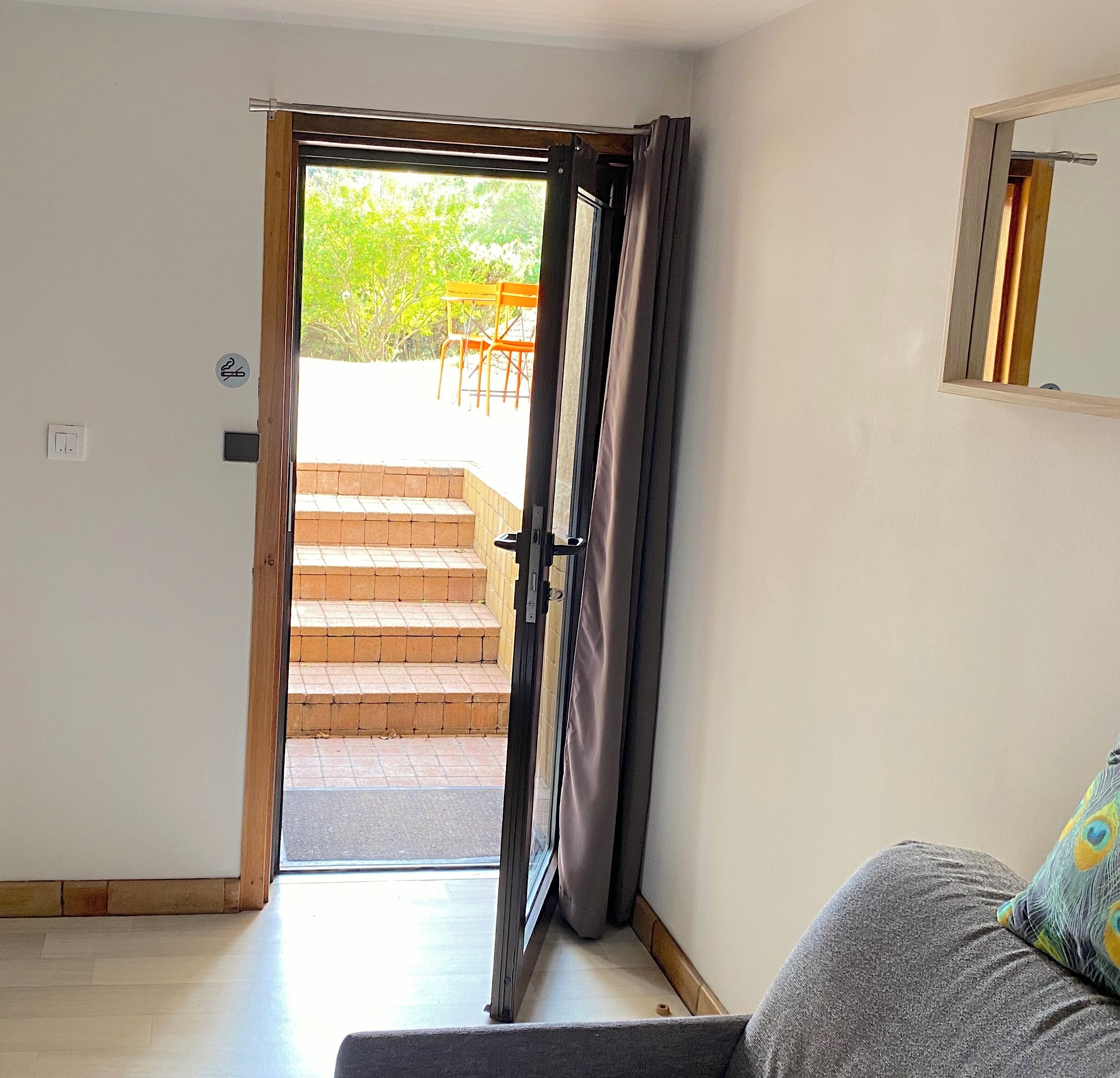 Une pièce dotée d’une porte coulissante donnant sur un patio aménagé avec du mobilier d’extérieur et un escalier.
