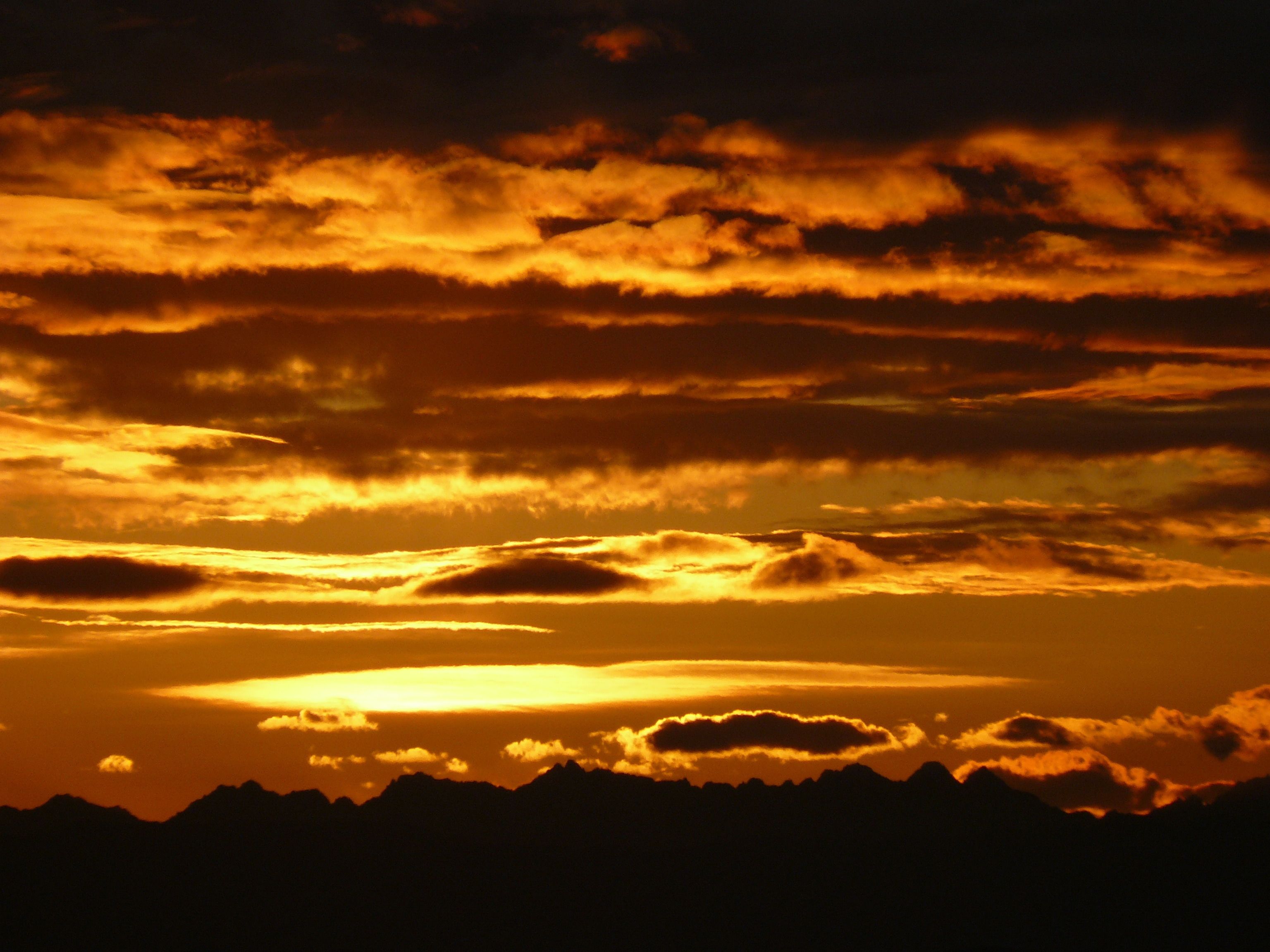 Silueta de una cadena montañosa contra un cielo de atardecer con nubes.