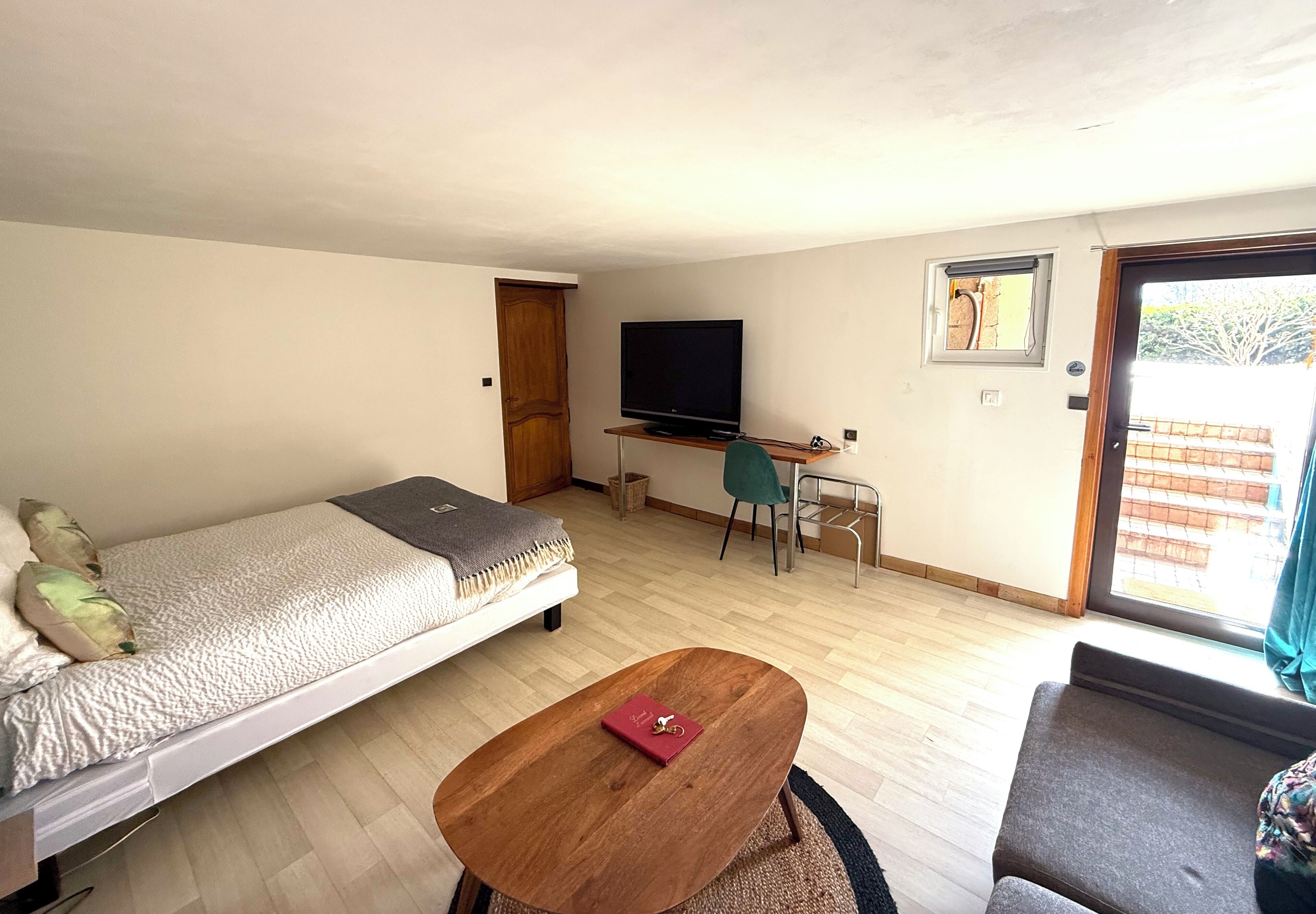 A compact room with a bed, a desk, a TV, and a window.