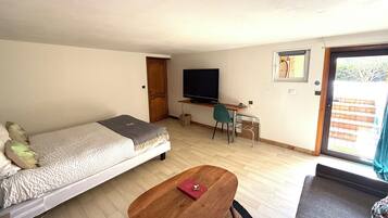 A compact room with a bed, a desk, a TV, and a window.