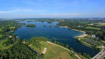 An aerial view of a lake surrounded by greenery and a few buildings.