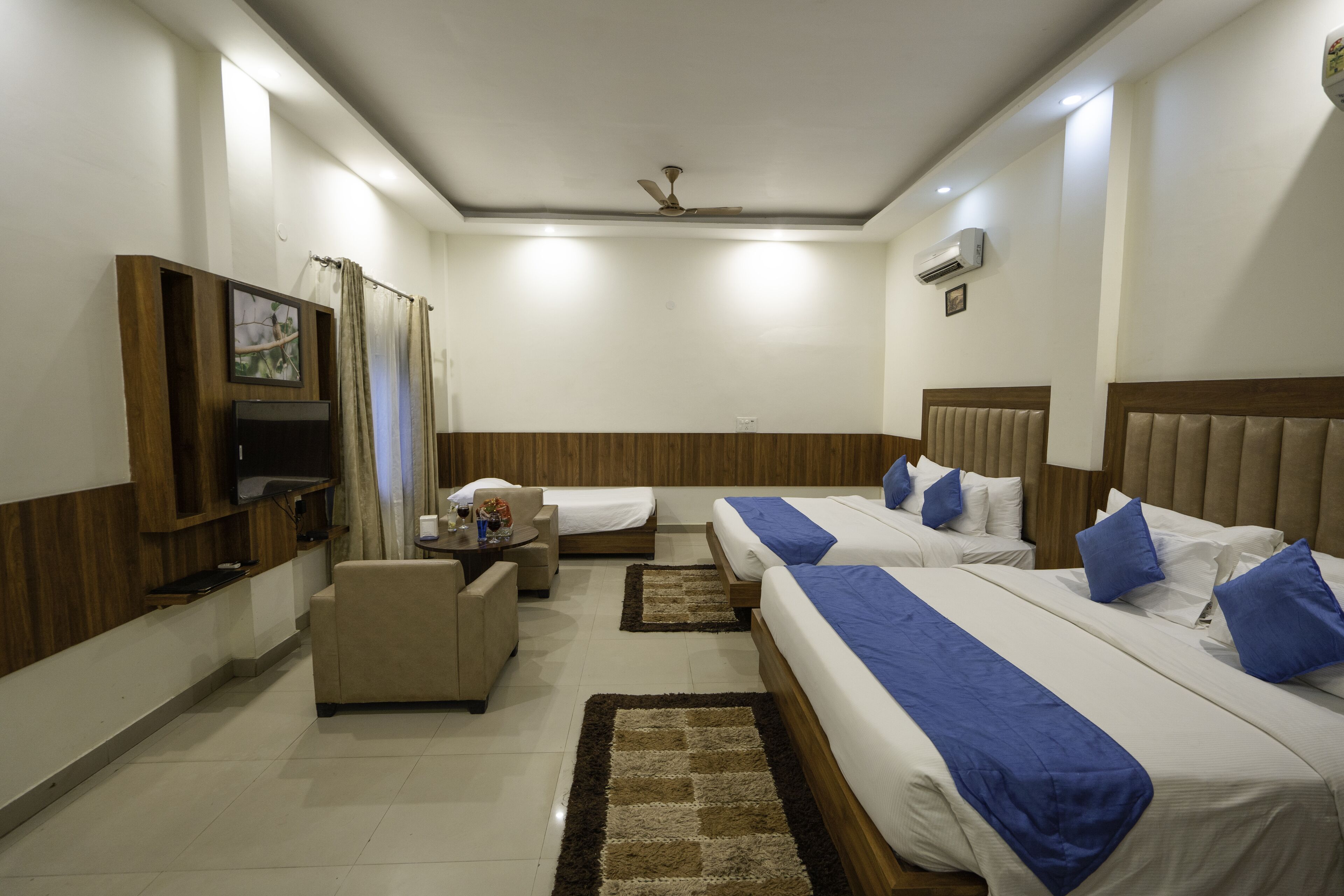 A hotel room with two beds, a TV, a desk, and a chair.