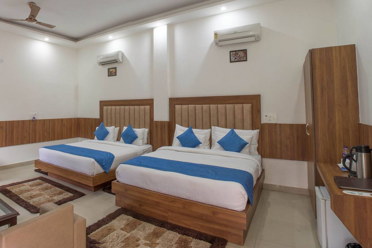 A hotel room with two beds, a sofa, a coffee table, and a desk with a laptop.