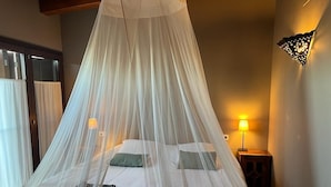 A bedroom with a canopy bed, a nightstand with a lamp, and a wall-mounted light fixture. - B&B El Ranxo (Caldes de Malavella)