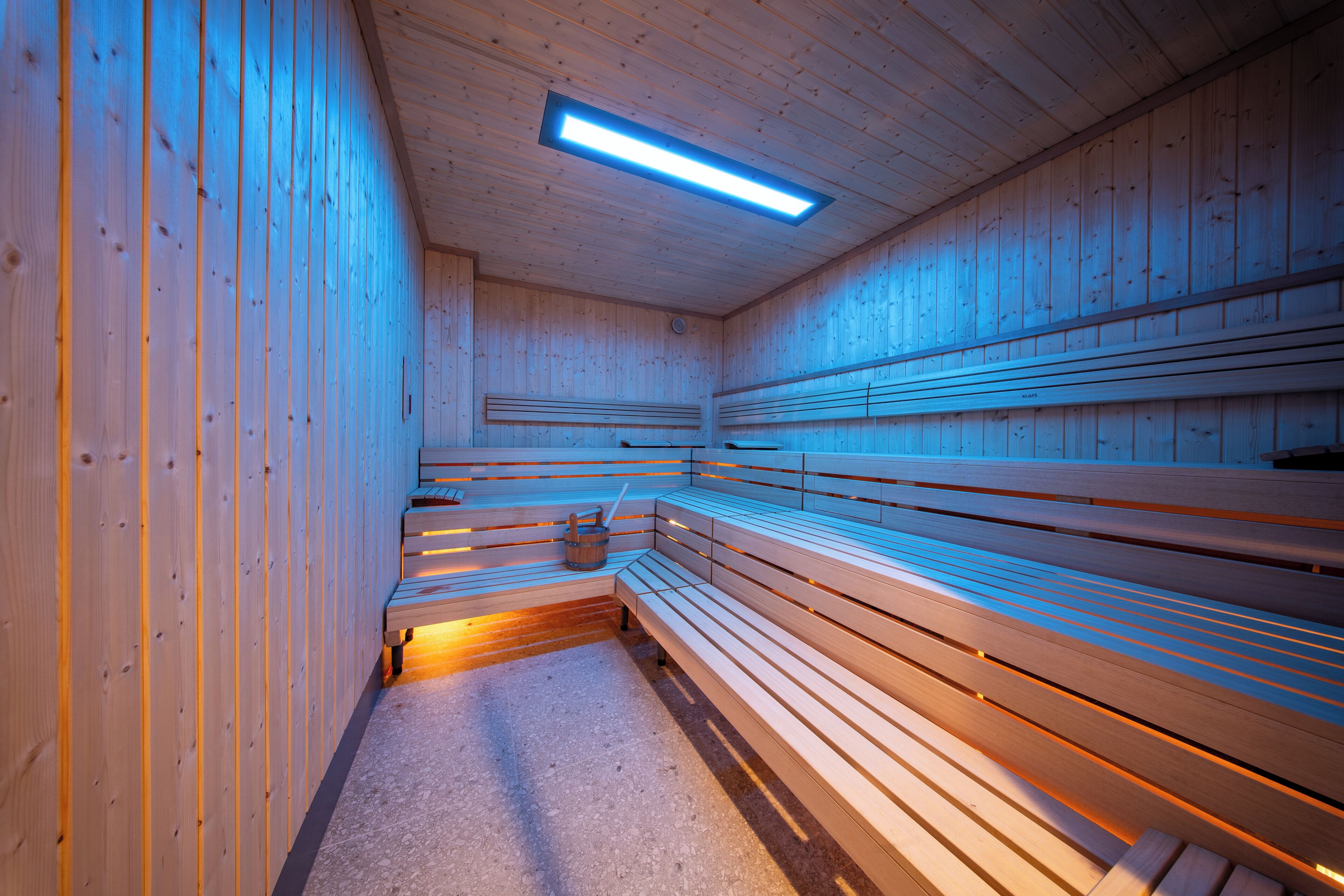 Un sauna avec des bancs en bois et un plancher incliné.