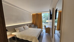 A modern hotel room with a large bed, a desk, a chair, and a mirror. - Family Hotel Adria (Biograd na Moru)