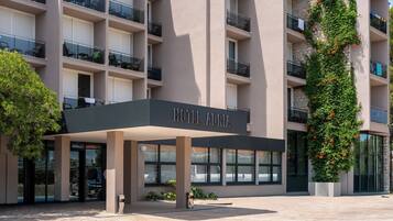 A hotel entrance with a covered area, multiple balconies, and a sign reading 'HOTEL ADRIA'.