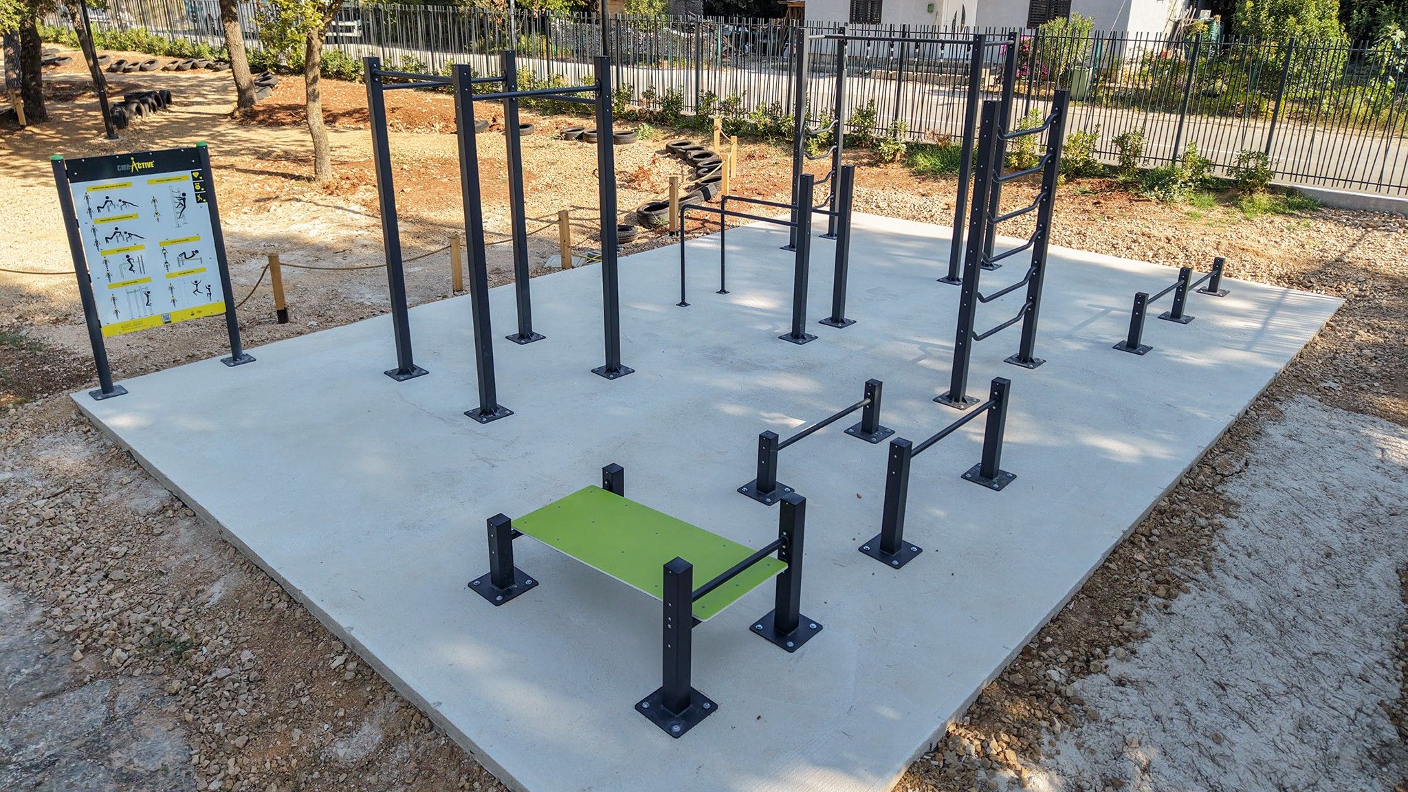 Un área de ejercicios al aire libre con varias barras de dominadas y un banco verde.
