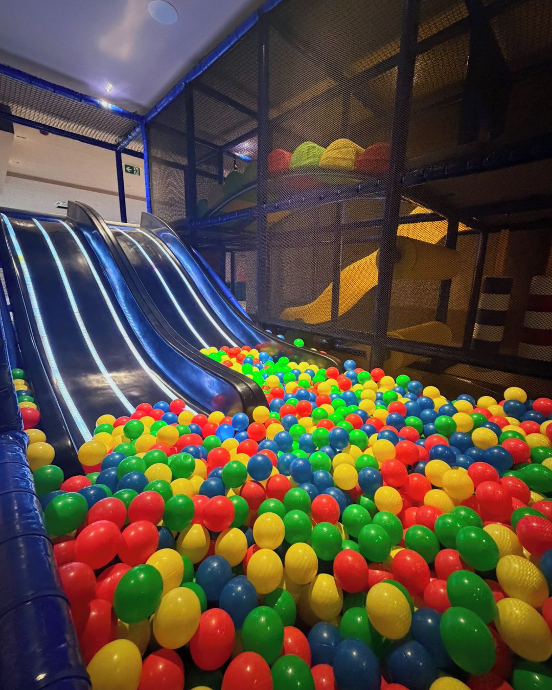 Un área de juegos interior con un tobogán y una piscina de pelotas llena de bolas multicolores.