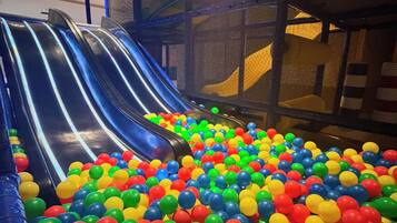 Un área de juegos interior con un tobogán y una piscina de pelotas llena de bolas multicolores.