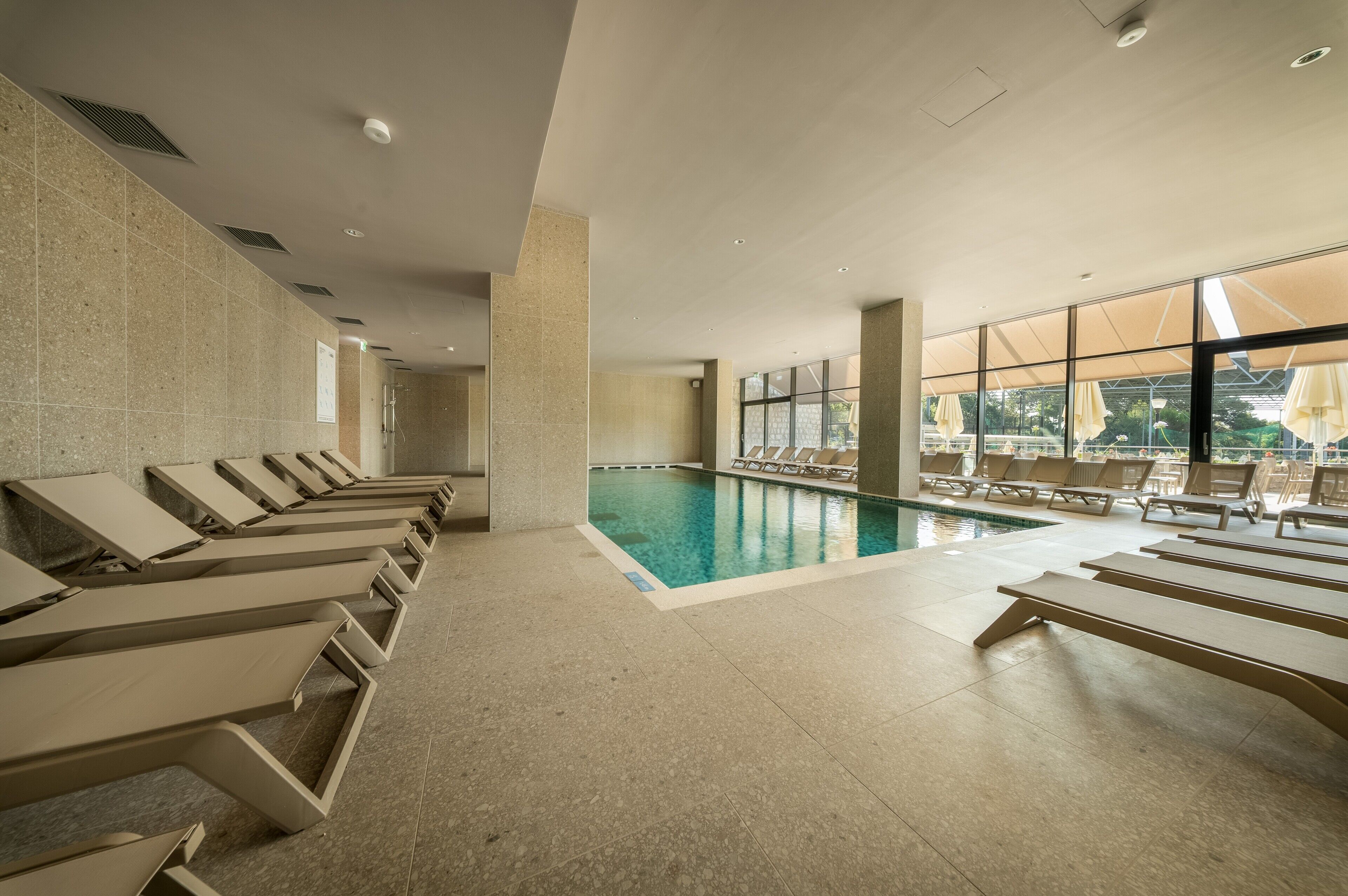 Un espace piscine avec des chaises longues et une vue sur l’extérieur.