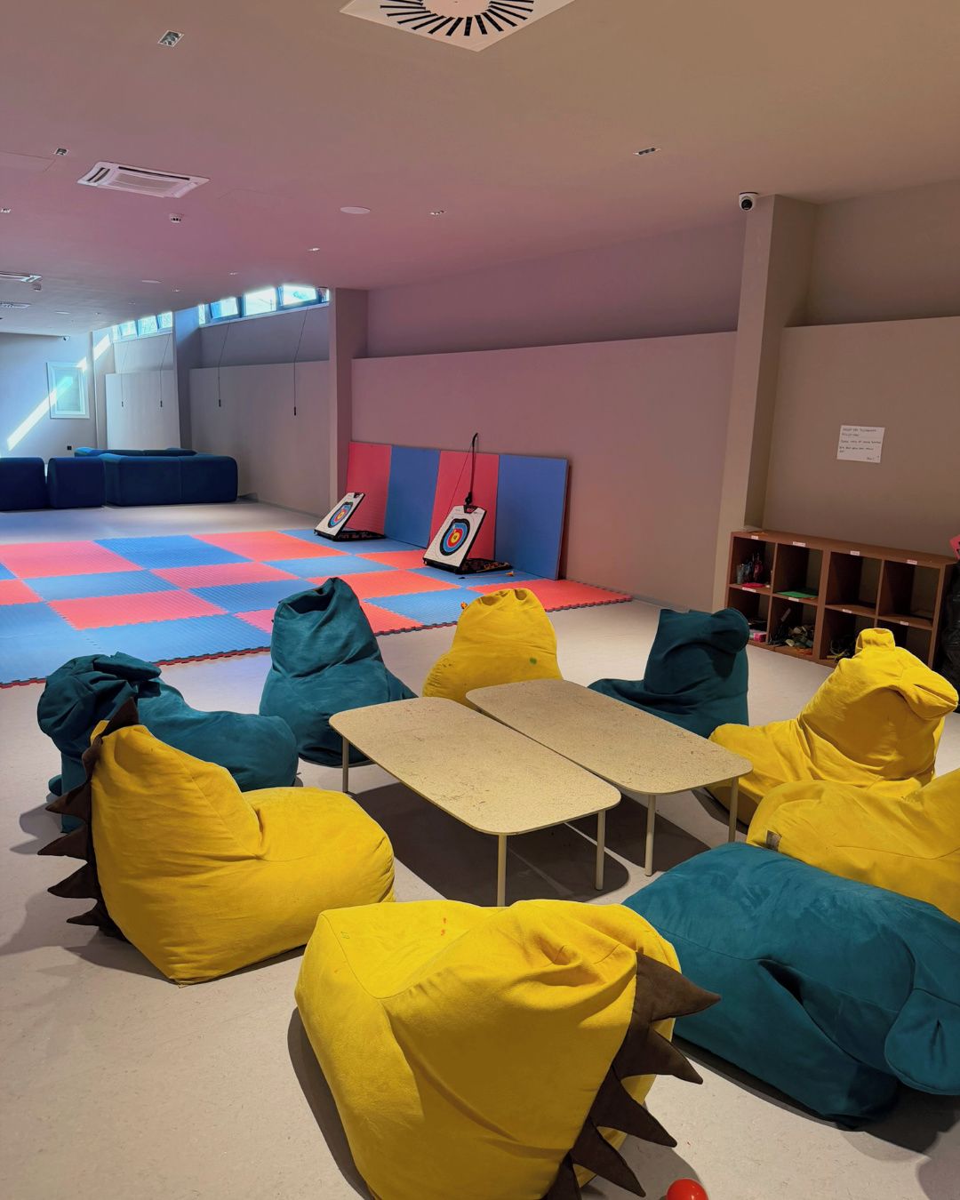 A room with colorful padded seating, a small table, and target boards on the wall.