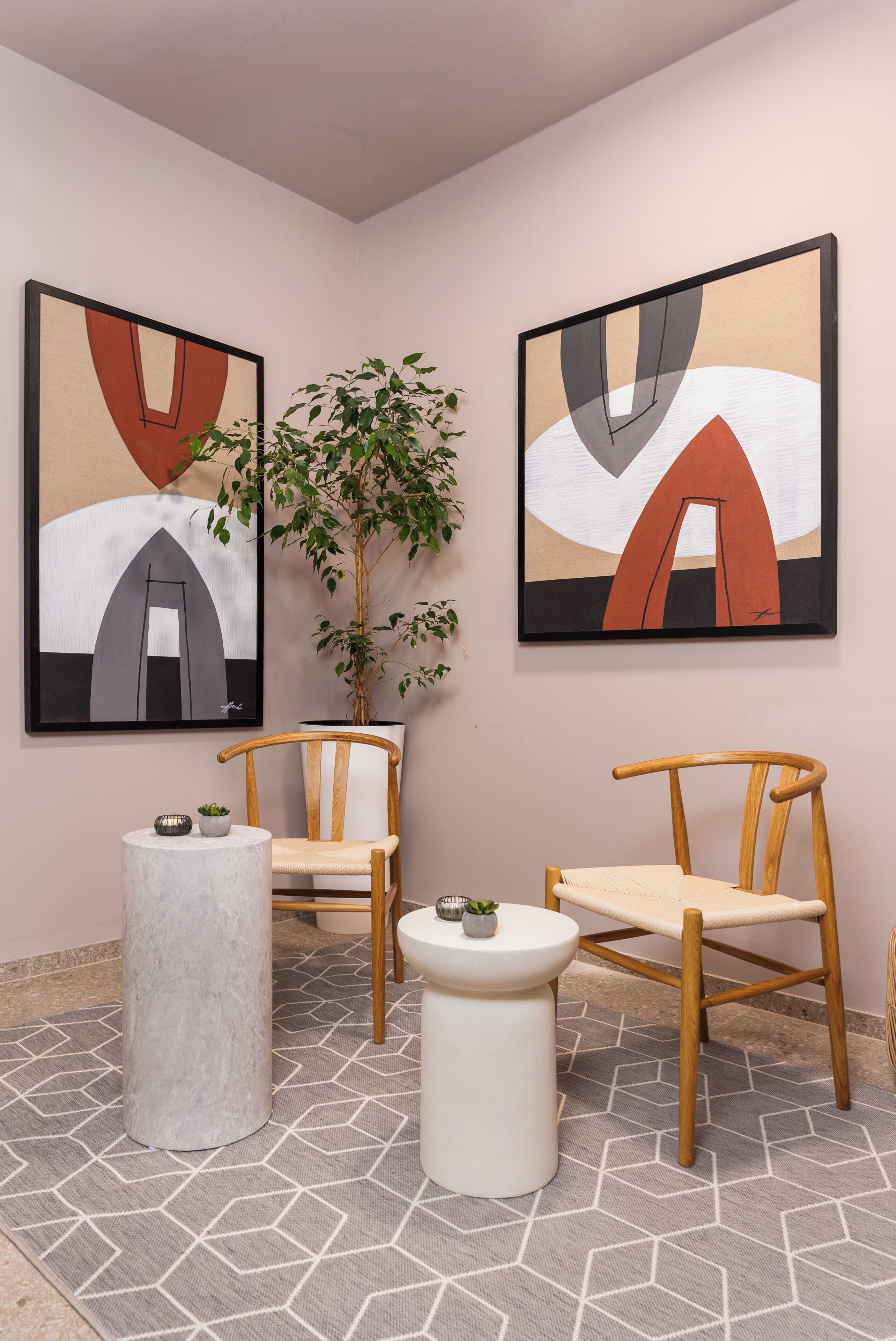 Un interior moderno con arte abstracto, sillas de madera, una mesa redonda y una planta en maceta.