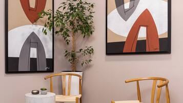 Un interior moderno con arte abstracto, sillas de madera, una mesa redonda y una planta en maceta.