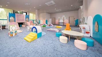 Ein Spielzimmer mit bunten Spielgeräten, einem Tisch und Sitzbereichen.
