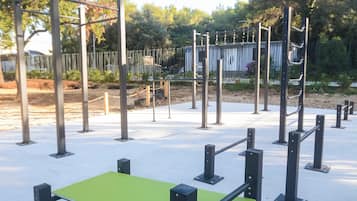An outdoor exercise area with a green platform and black metal poles.