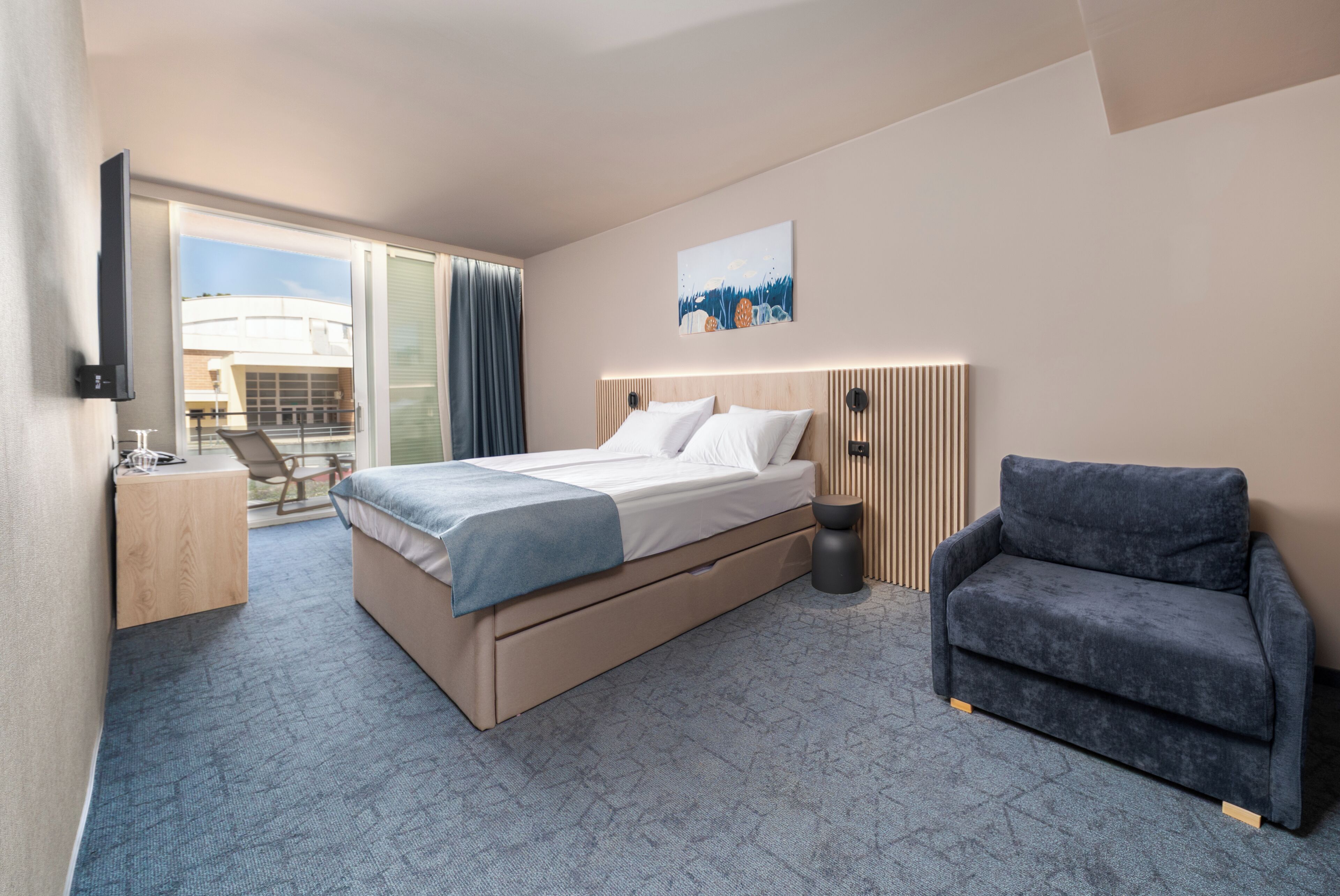 Une chambre d’hôtel avec un lit, une chaise, un bureau et un téléviseur.