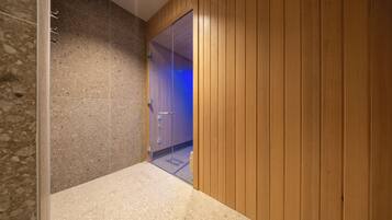 Un pasillo con una pared de piedra en un lado y paneles de madera en el otro, que conduce a una habitación con una puerta.