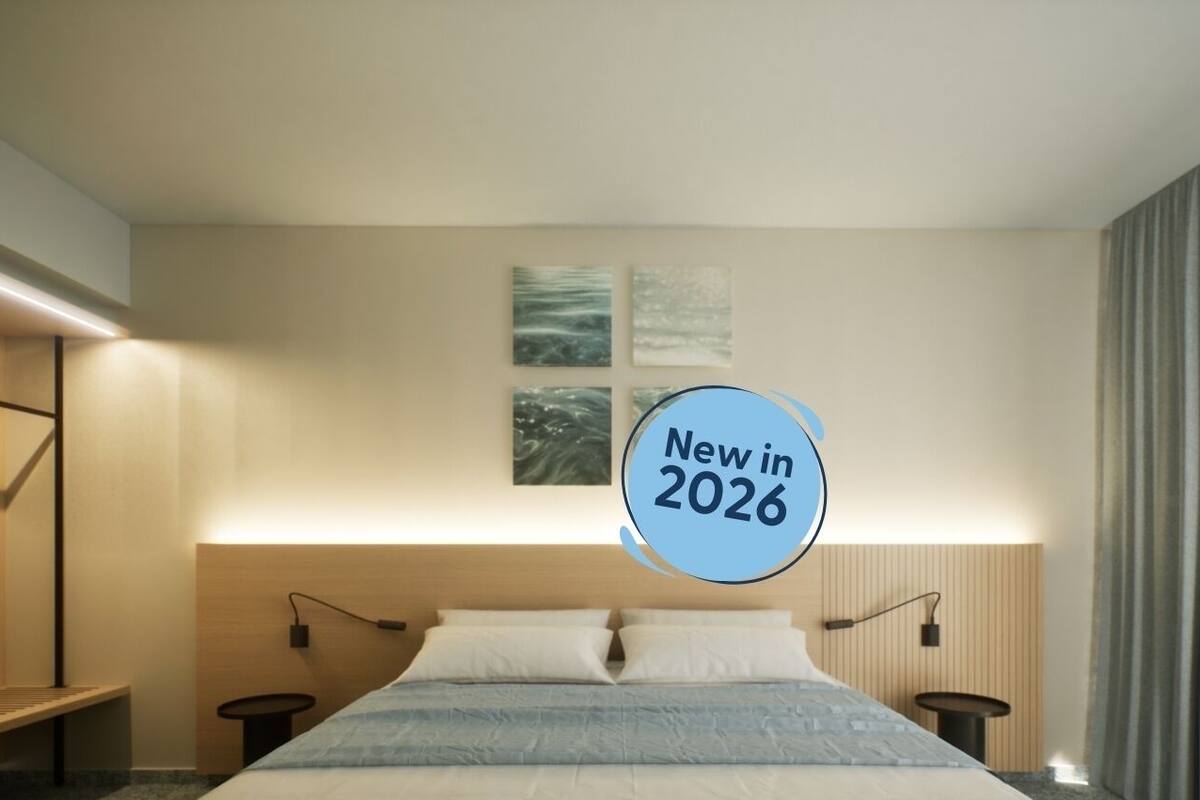 A modern hotel room with a large bed, bedside tables, and wall-mounted artwork.