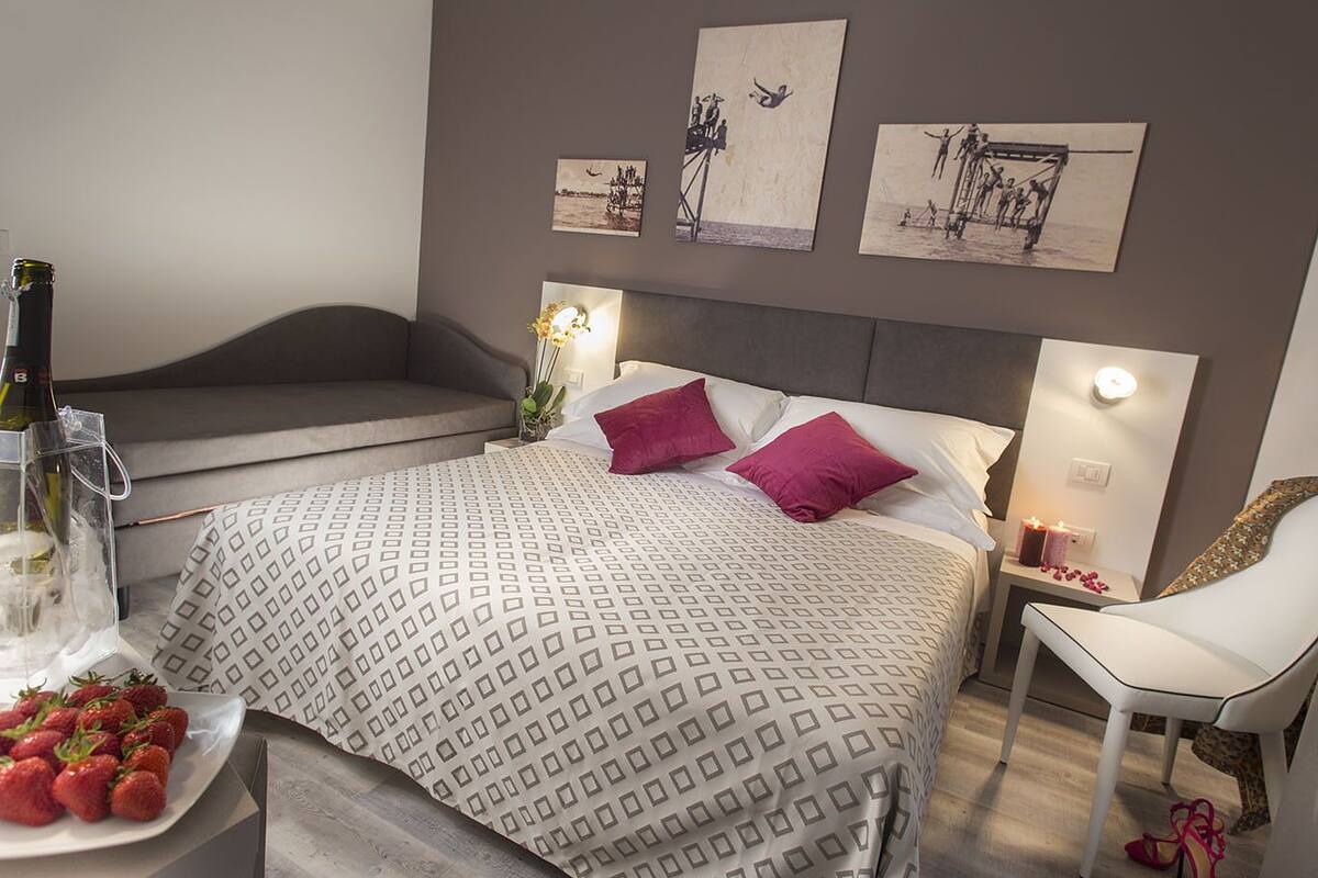 A bedroom with a bed, bedside tables, a chair, and artwork on the wall.