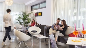 Una sala moderna con un sofá, sillas, una mesa de centro y una mesa de comedor con bebidas.
