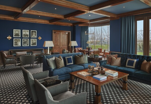 A spacious living room with a blue sofa set, a wooden coffee table, and patterned flooring.