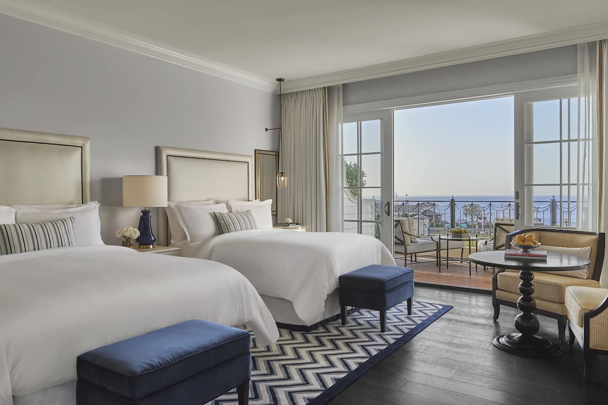 Een hotelkamer met twee bedden, een balkon en een eethoek.