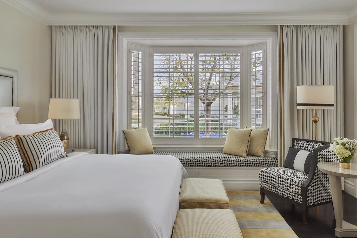 Hotelkamer met een groot bed, een zithoek bij het raam en een kleine tafel met lamp.