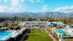 A large resort with multiple guest rooms, a swimming pool, and a well-maintained lawn.