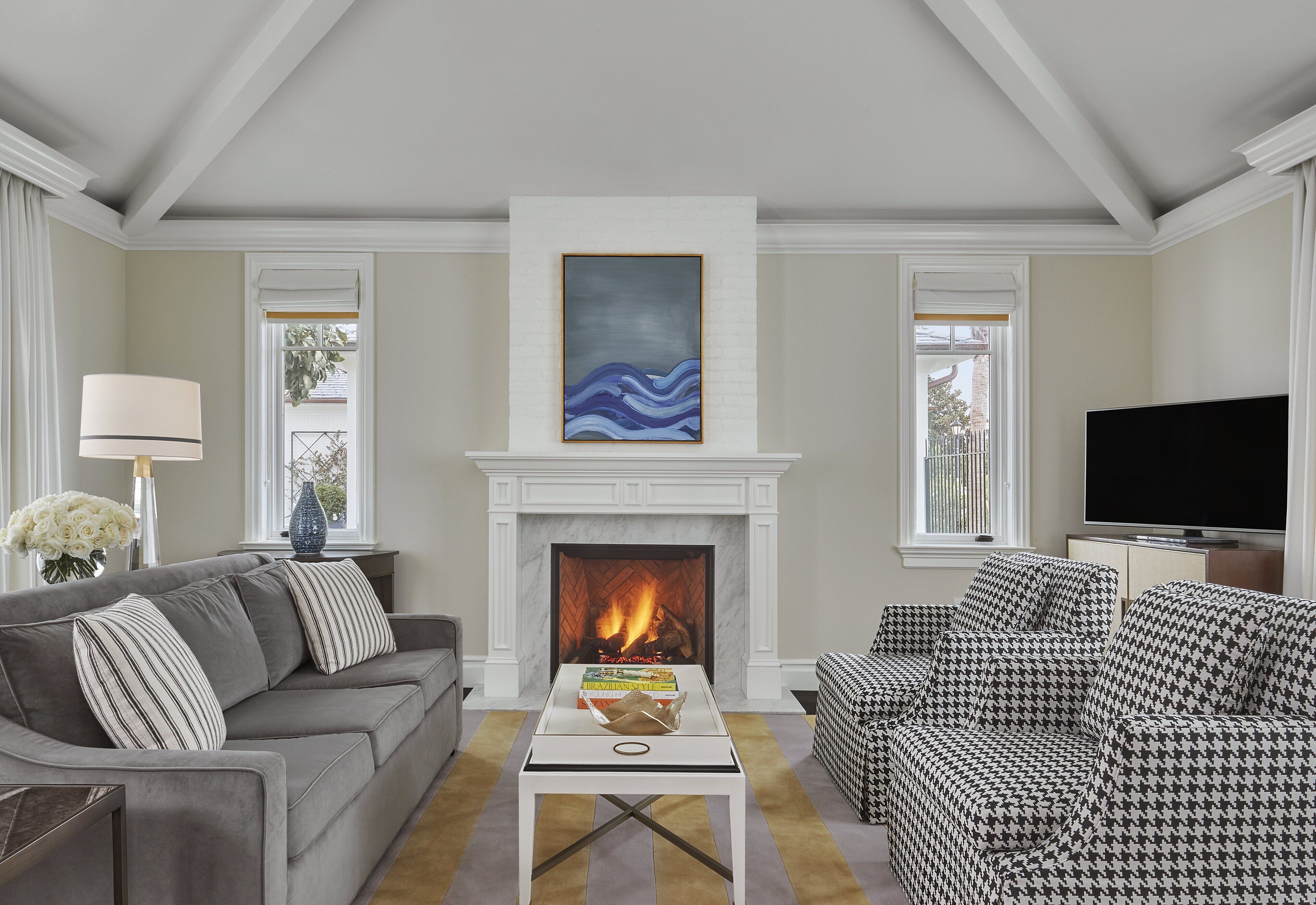 Una sala de estar con chimenea, un sofá, un sillón estampado y un televisor.