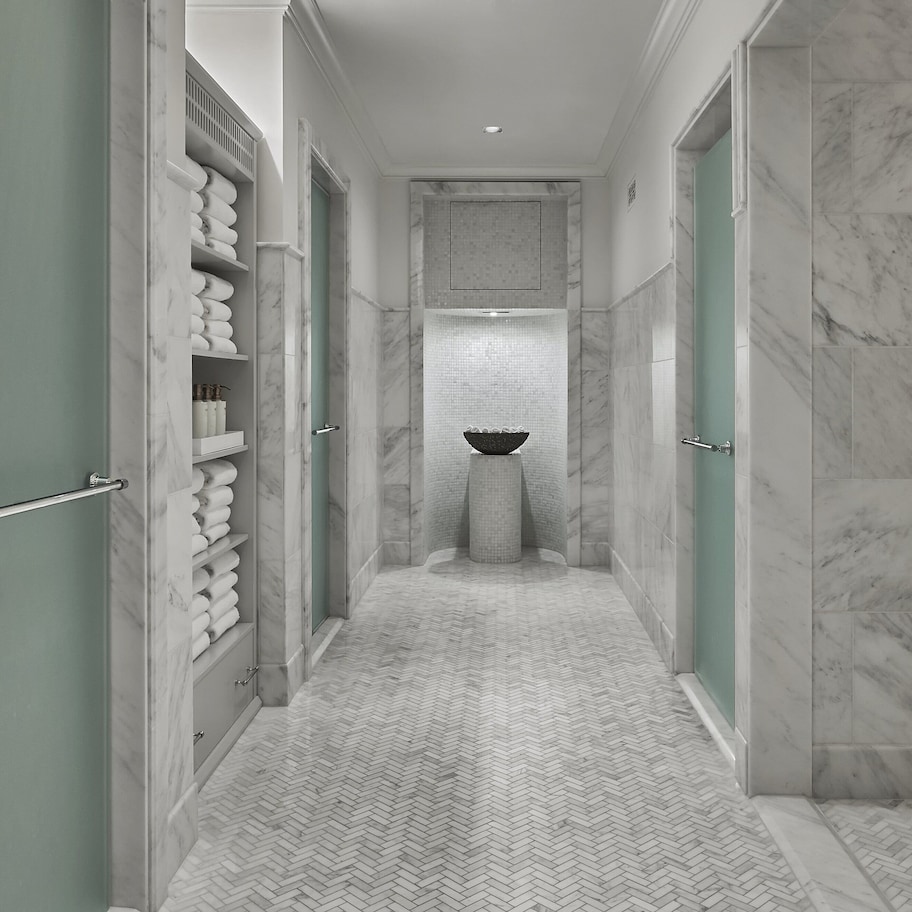 A hallway with marble flooring, a central sink, and a towel rack on the left.