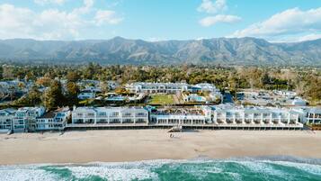 Un complejo turístico frente a la playa, con villas, piscina y vistas a montañas.