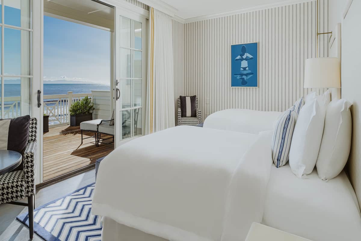 Een hotelkamer met een groot bed, een zithoek met uitzicht op zee en een schilderij aan de muur.