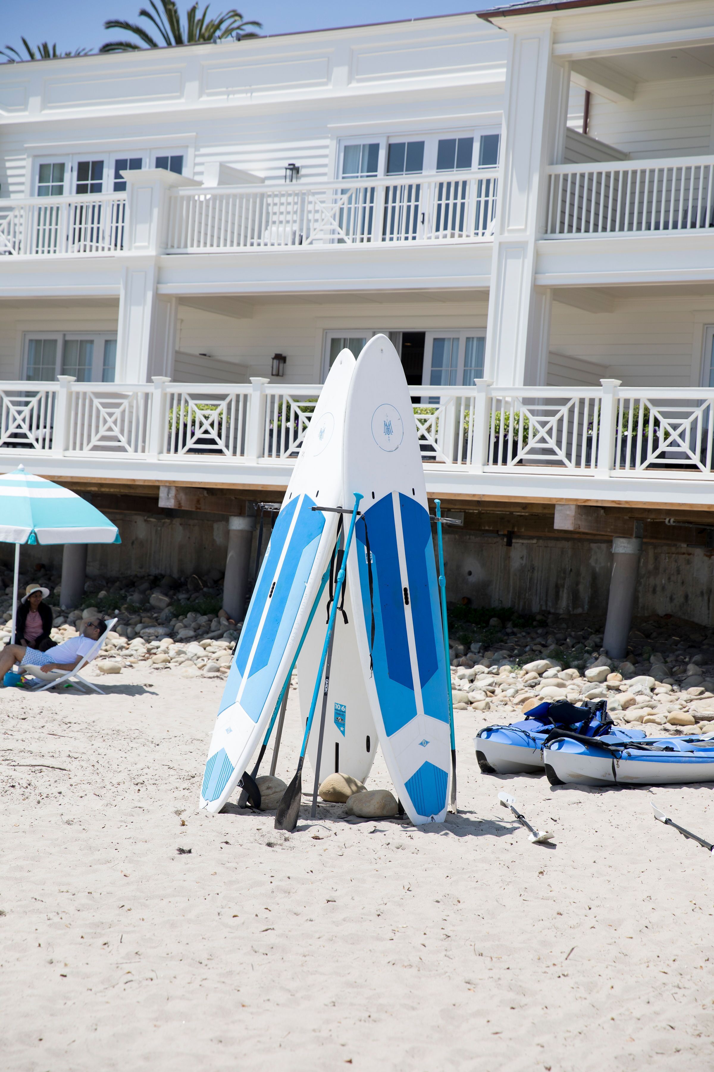Una playa con tablas de surf y una sombrilla.